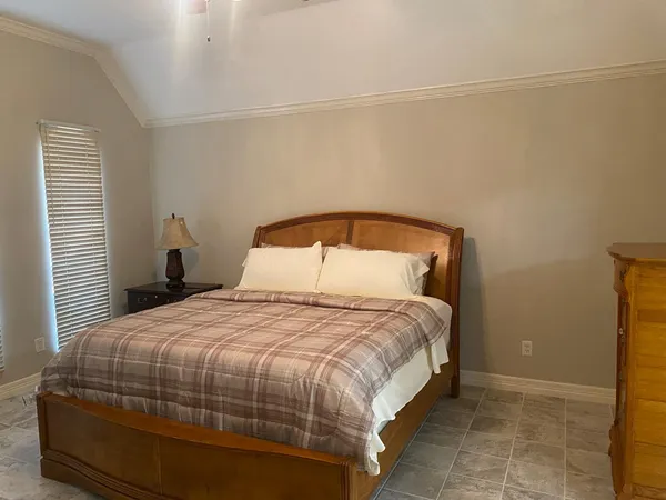 a bedroom with a bed and a potted plant on the dresser