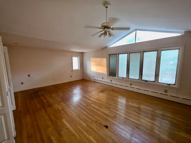 a view of an empty room with a window and wooden floor