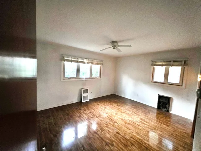 a view of an empty room with window and wooden floor
