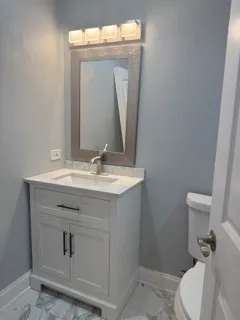 a bathroom with a sink vanity mirror and toilet