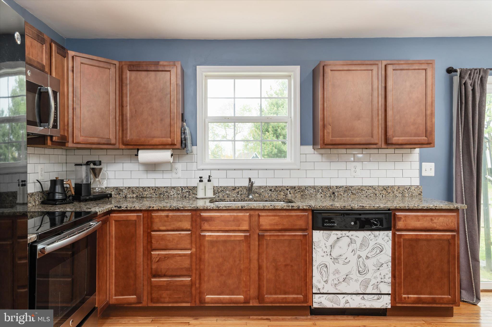 200 Newtown Road Chester, MD 21619 - Photo 15 of 50 a kitchen with granite countertop wooden cabinets stainless steel appliances a sink and a window