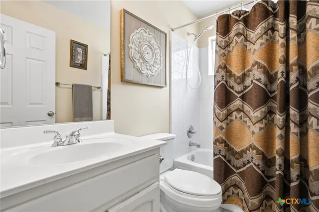a bathroom with a granite countertop toilet sink and mirror