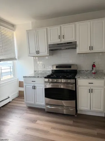 a kitchen with granite countertop white cabinets and a stove a sink