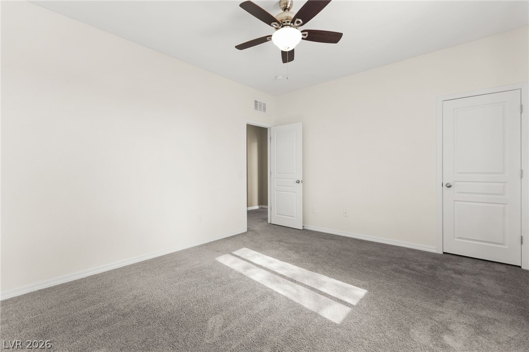 11048 Prairie Grove Road Las Vegas, NV 89179 - Photo 53 of 75 A well-lit bedroom features plush carpeting and a modern ceiling fan, ready for your personal touch.