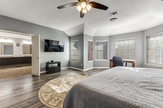 a bedroom with bed and a flat tv screen on dresser