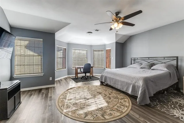 a spacious bedroom with a bed and wooden floor