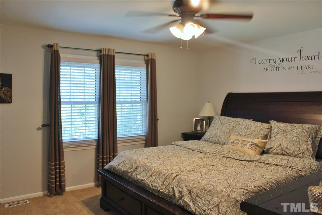 4004 Grimstead Lane Raleigh, NC 27613 - Photo 12 of 25 a bedroom with a large bed and a chandelier