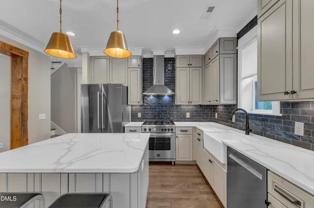 a kitchen with stainless steel appliances a sink a stove a refrigerator cabinets and living room view