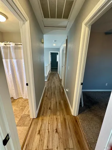 a view of a hallway with wooden floor and staircase