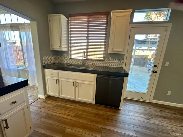 a kitchen with granite countertop white cabinets and wooden floor