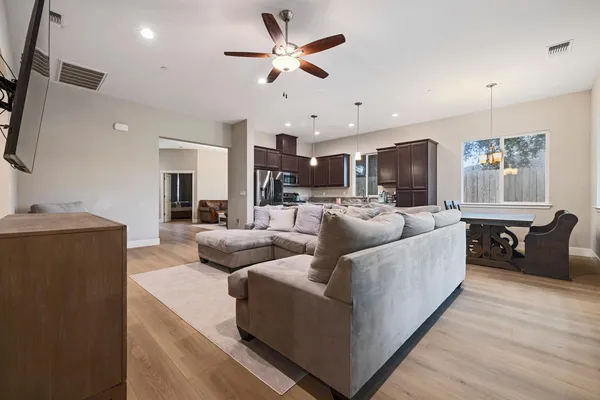 a living room with furniture kitchen view and a wooden floor