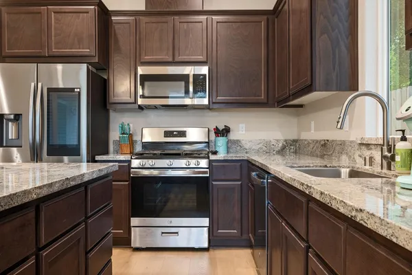 a kitchen with stainless steel appliances granite countertop a sink stove and microwave