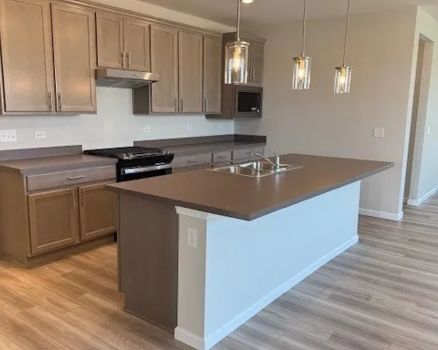 a kitchen with kitchen island granite countertop a sink a stove and a wooden floors