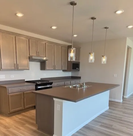 a kitchen with kitchen island granite countertop a sink a counter space appliances and cabinets