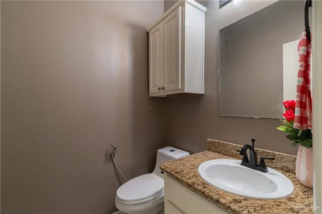 a bathroom with a granite countertop sink and a mirror with toilet