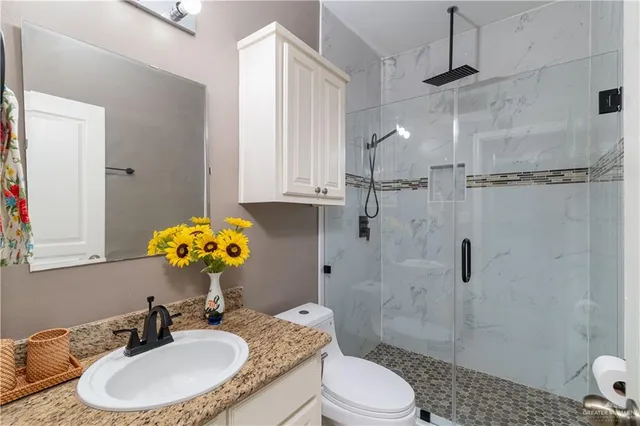 a bathroom with a granite countertop sink toilet a mirror and shower