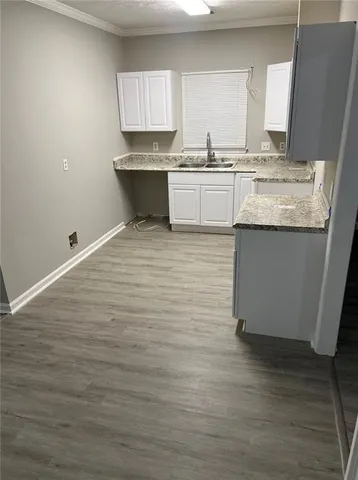 a kitchen with granite countertop a sink cabinets and wooden floor