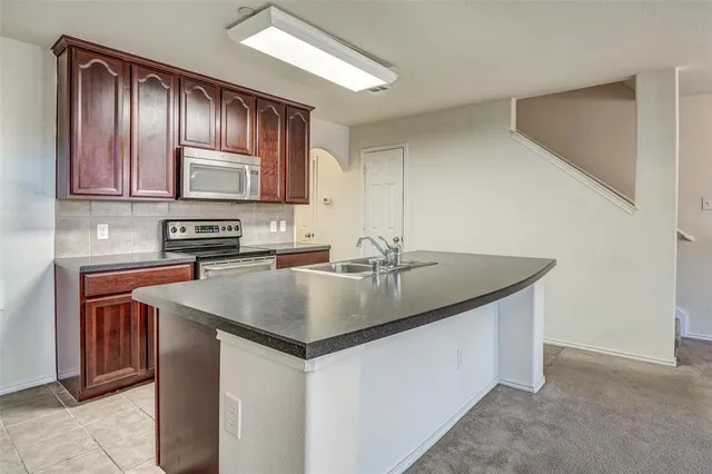 a kitchen with stainless steel appliances granite countertop a sink a microwave refrigerator and cabinets