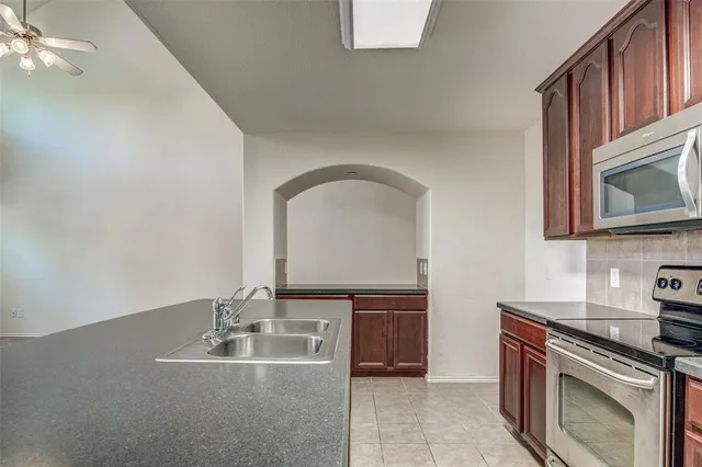 a kitchen with kitchen island granite countertop a stove top oven a sink and dishwasher