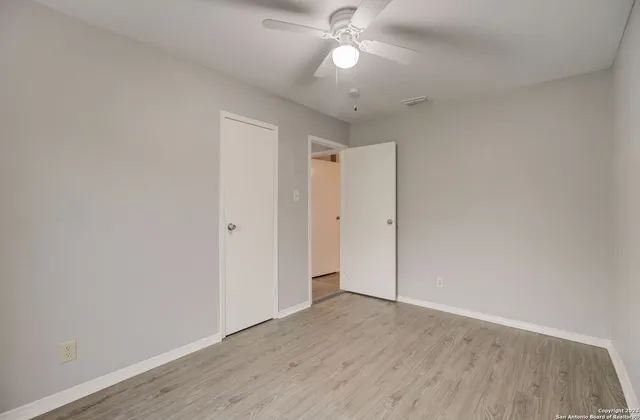 an empty room with wooden floor and fan