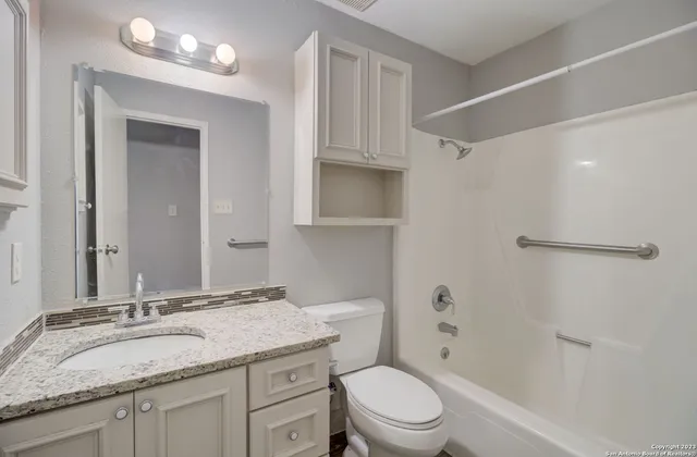 a bathroom with a granite countertop sink toilet a mirror and shower