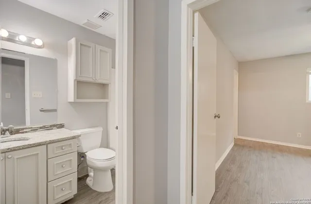 a bathroom with a granite countertop toilet a sink and a mirror
