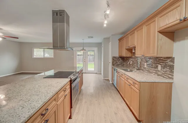 a kitchen with granite countertop a sink stove and cabinets