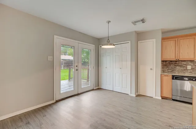 a view of an empty room with window and hardwood floor