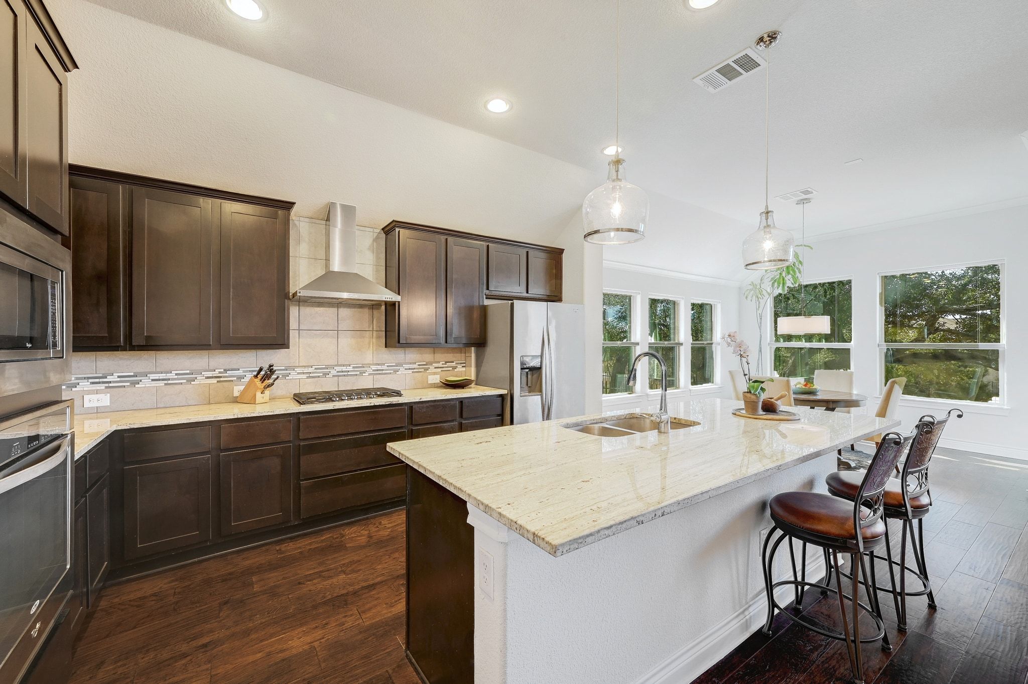 960 Blue Ridge Drive Dripping Springs, TX 78620 - Photo 7 of 38 Kitchen featuring light stone countertops, dark wood finish cabinetry, stainless steel appliances, backsplash, and dark wood-style flooring