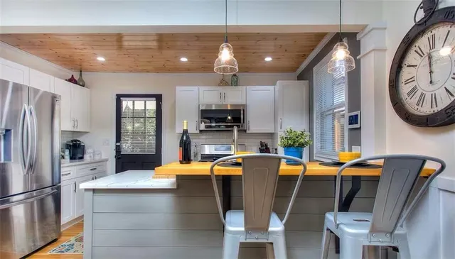 a dining hall with stainless steel appliances granite countertop a dining table chairs refrigerator and stove