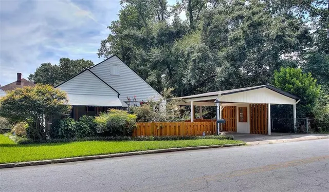 a view of a house with a yard and large trees