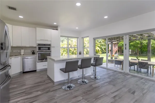 a kitchen with stainless steel appliances wooden floor and refrigerator