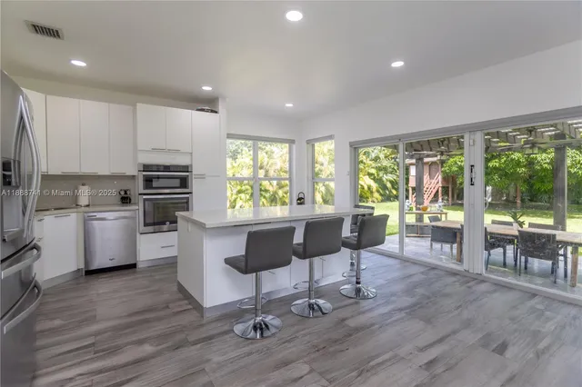 a kitchen with stainless steel appliances wooden floor and refrigerator