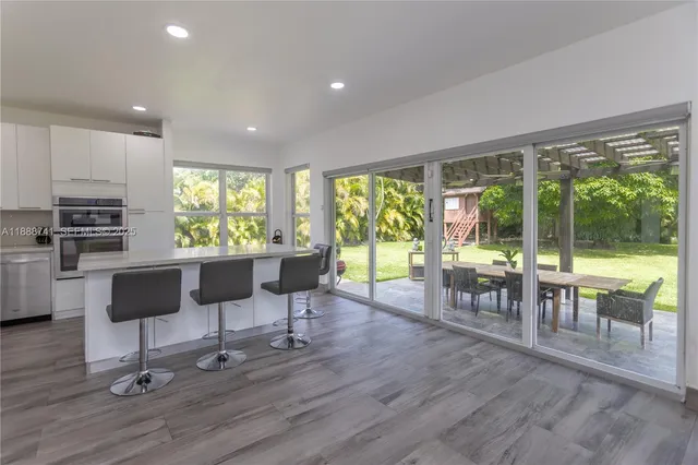 a living room with furniture a wooden floor and kitchen view
