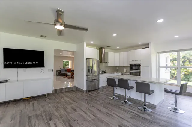 a living room with furniture a wooden floor and kitchen view