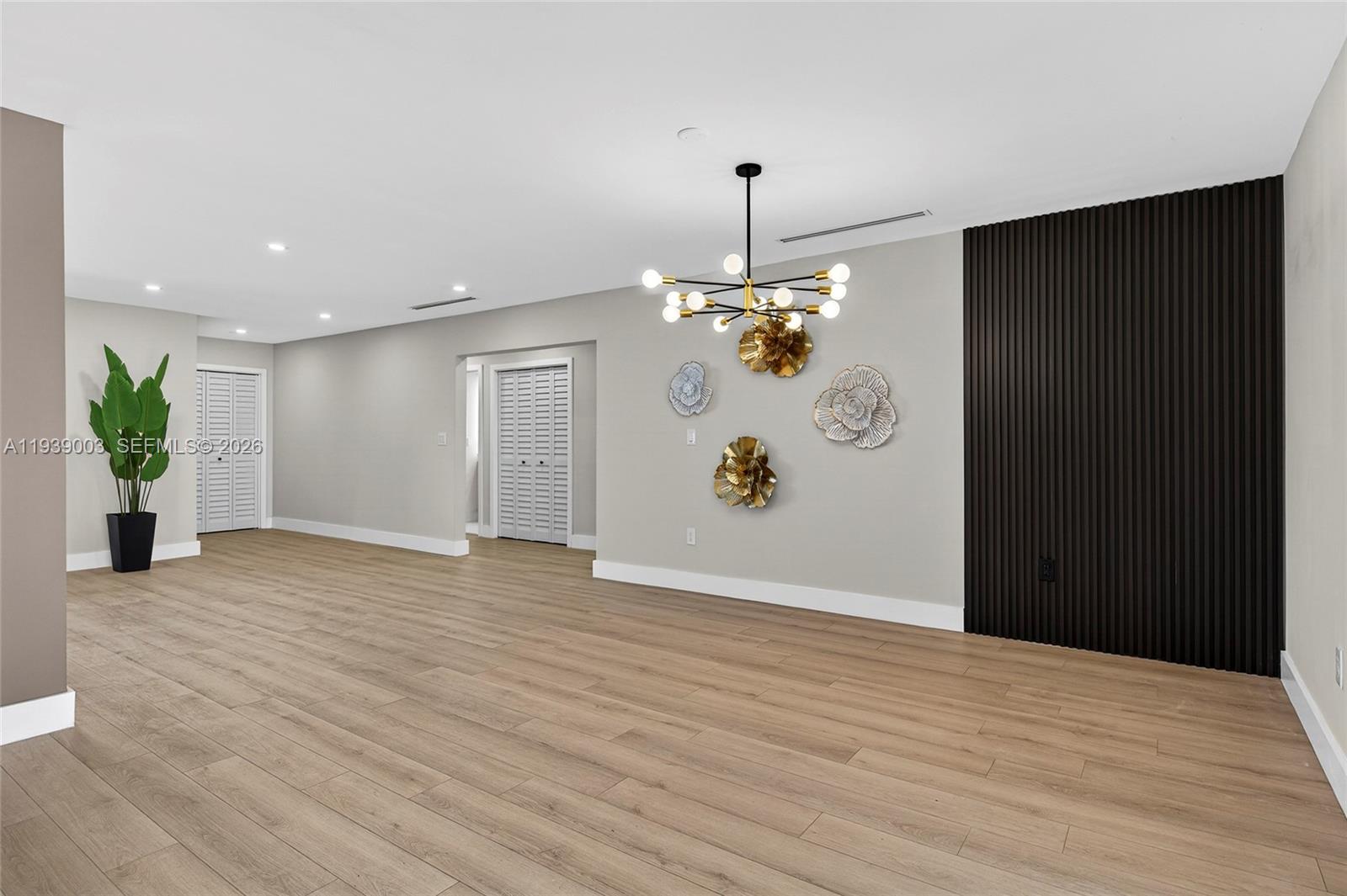 4712 Cleveland Street Hollywood, FL 33021 - Photo 14 of 49 a view of an empty room with wooden floor and a chandelier