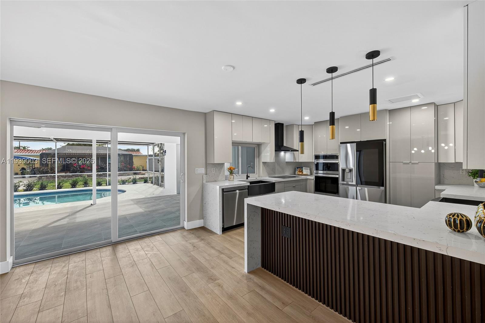 4712 Cleveland Street Hollywood, FL 33021 - Photo 21 of 49 a large kitchen with stainless steel appliances kitchen island a large counter top and wooden floors