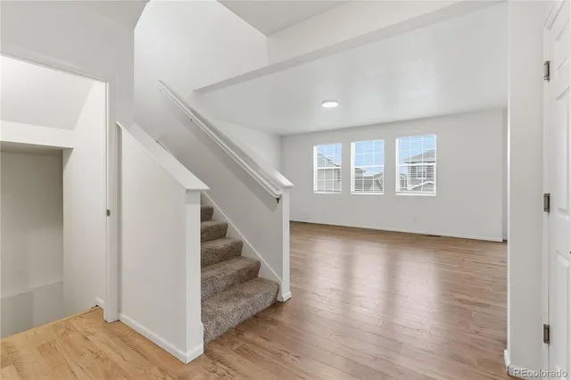 a view of an empty room with wooden floor and stairs