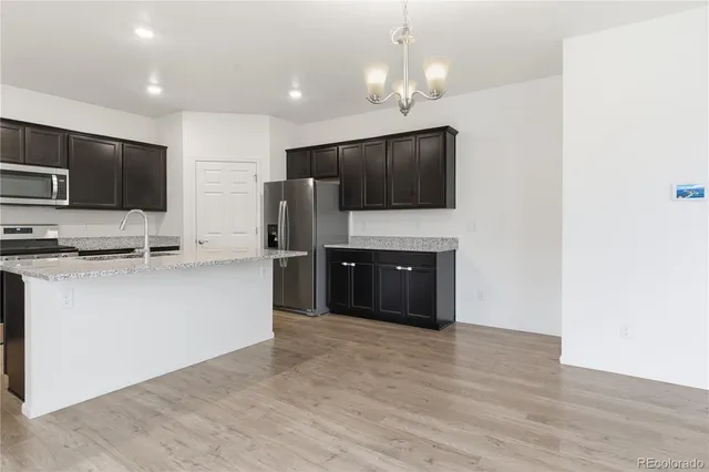 a large kitchen with stainless steel appliances a large counter top a stove a microwave and a refrigerator