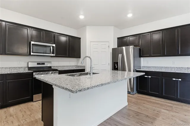 a kitchen with stainless steel appliances wooden cabinets a refrigerator and a stove top oven