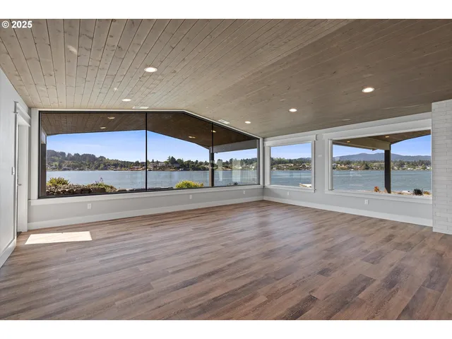 a view of an empty room with wooden floor and a large window