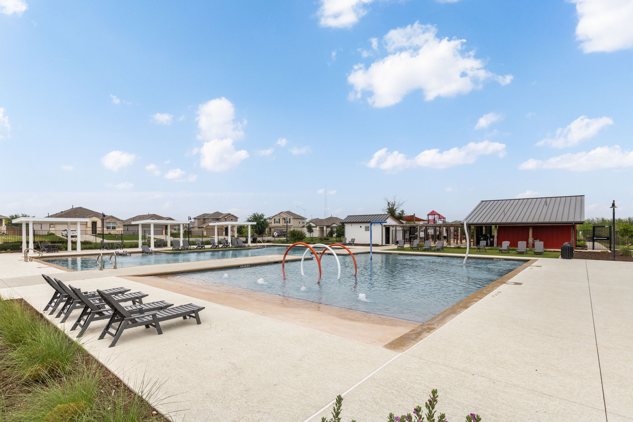 281 Jayden Drive Kyle, TX 78640 - Photo 34 of 36 Expansive community pool area featuring multiple swimming pools, a shallow entry pool with water features, and surrounding concrete decking