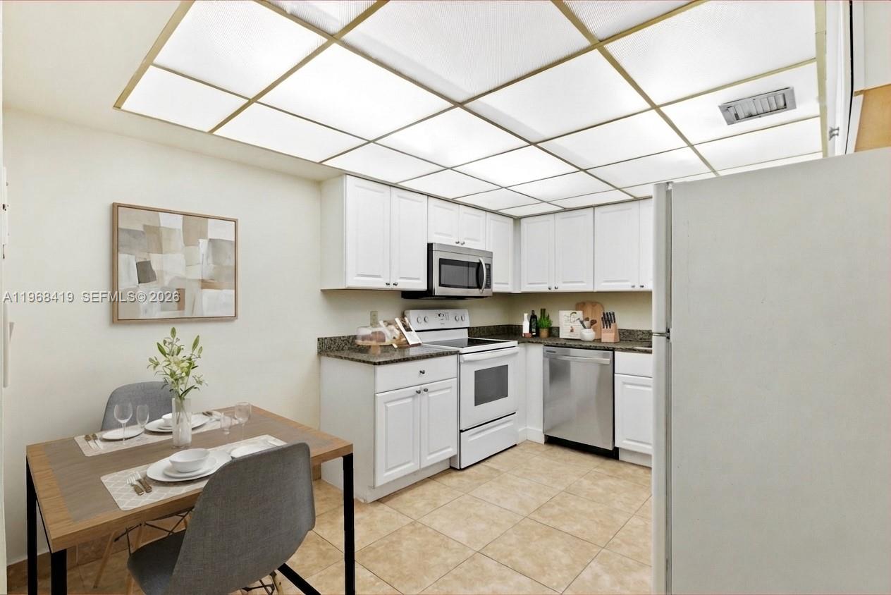 16400 Golf Club Road, Unit 104 Weston, FL 33326 - Photo 13 of 24 a kitchen with stainless steel appliances granite countertop a sink dishwasher a stove a microwave oven with a dining table and chairs