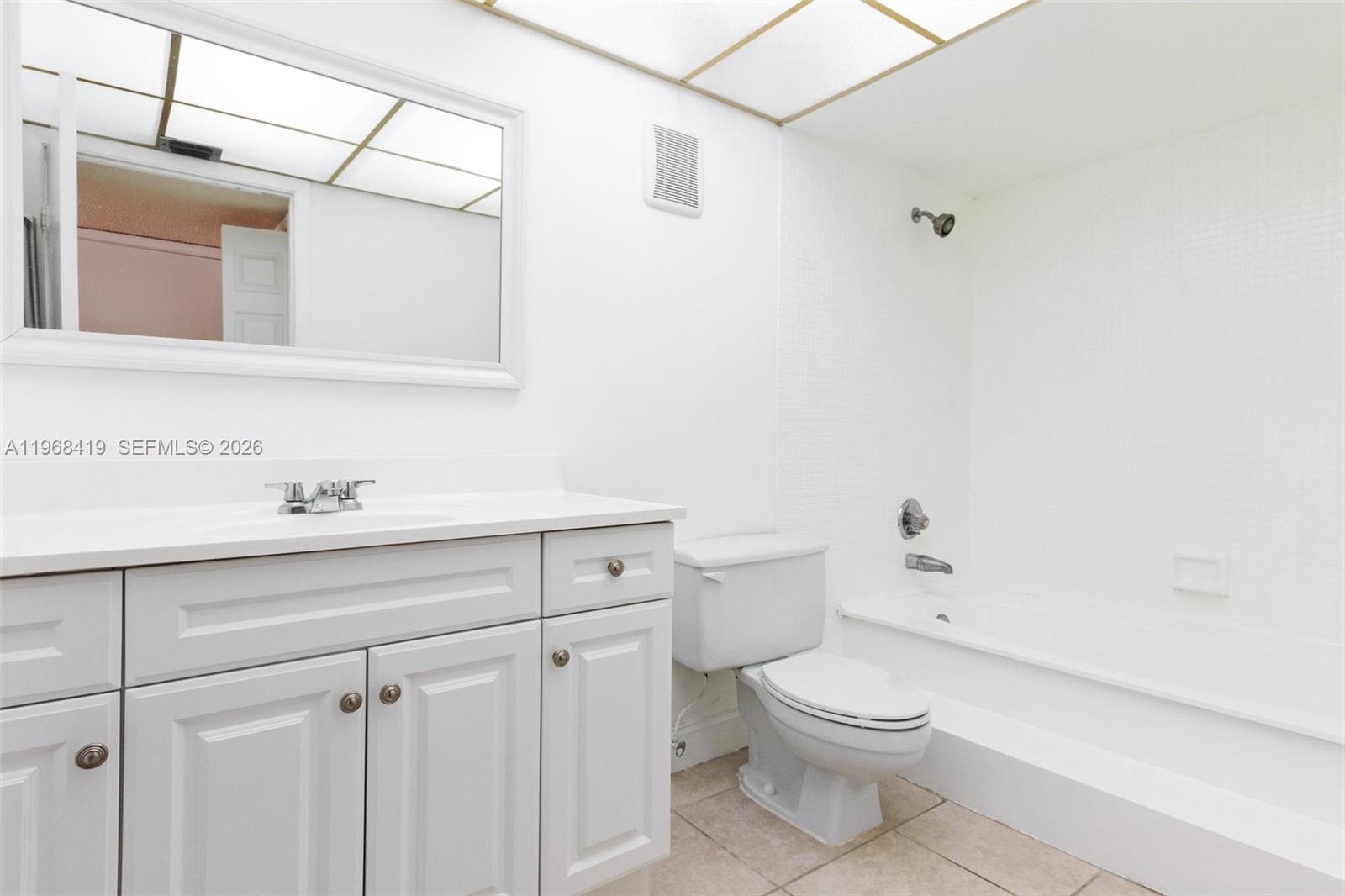 16400 Golf Club Road, Unit 104 Weston, FL 33326 - Photo 18 of 24 a bathroom with a toilet a sink a mirror and vanity