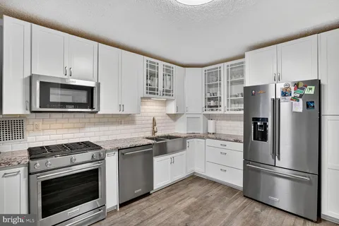 a kitchen with cabinets stainless steel appliances and wooden floor