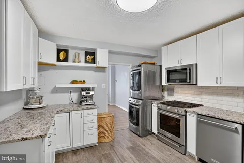 a kitchen with granite countertop stainless steel appliances a stove microwave and sink
