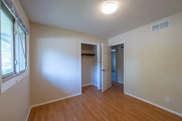 an empty room with wooden floor and windows