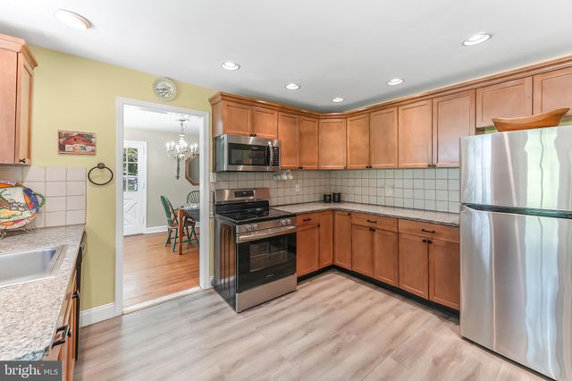 a kitchen with stainless steel appliances granite countertop a refrigerator a sink dishwasher a stove with wooden cabinets and floor