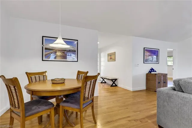 a kitchen with stainless steel appliances granite countertop a stove a refrigerator a sink a dining table and chairs with wooden floor