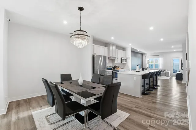 a kitchen with stainless steel appliances a refrigerator a stove a sink dishwasher and a dining table with wooden floor